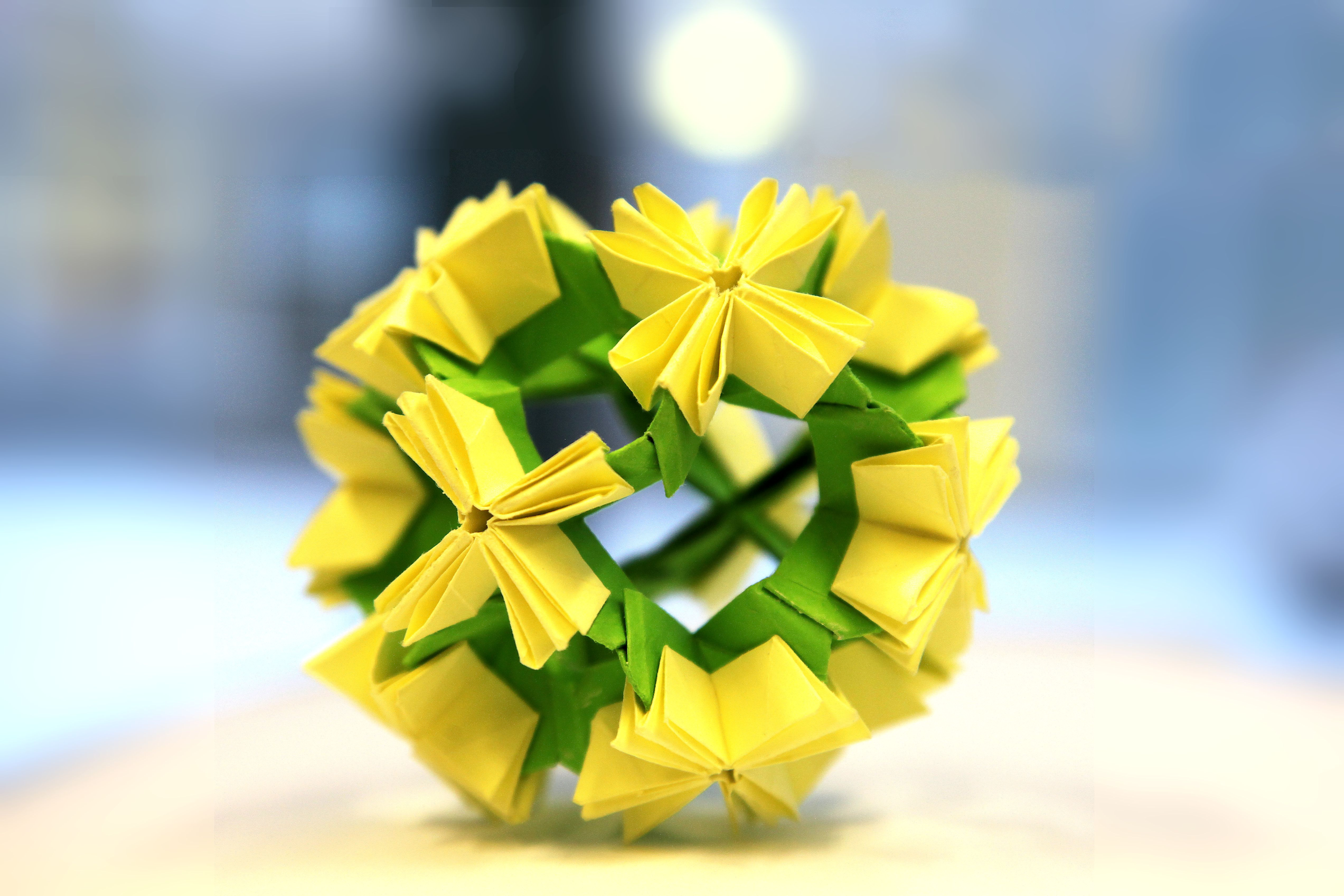 Kuvassa on vihreän ja keltaisen värinen pyöreä paperista taiteltu pallo.
